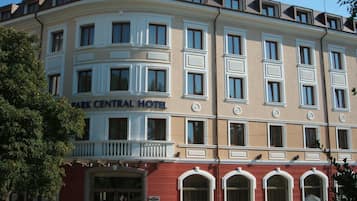 A multi-story building with a central entrance, balconies, and a sign reading 'Park Central Hotel'.