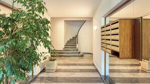 A modern interior with a curved staircase, potted plants, and built-in storage units. - Lion Apt - Near City Center - Terrace, Nice, France (Nice)