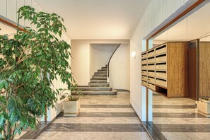 A modern interior with a curved staircase, potted plants, and built-in storage units. - Lion Apt - Near City Center - Terrace, Nice, France (Nice)