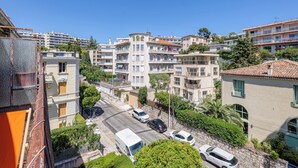 A residential area with multi-story buildings, a street with parked cars, and a clear blue sky. - Lion Apt - Near City Center - Terrace, Nice, France (Nice)