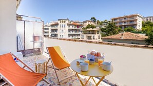 A balcony with a table set for breakfast, a chair, and a view of the cityscape. - Lion Apt - Near City Center - Terrace, Nice, France (Nice)