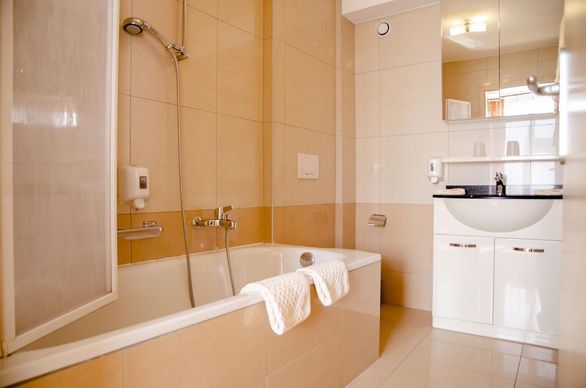 A modern bathroom with a bathtub, a shower, and a sink.