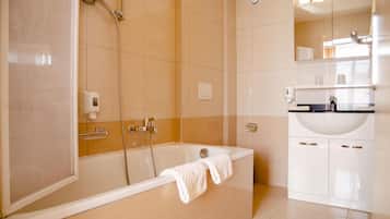 A modern bathroom with a bathtub, a shower, and a sink.