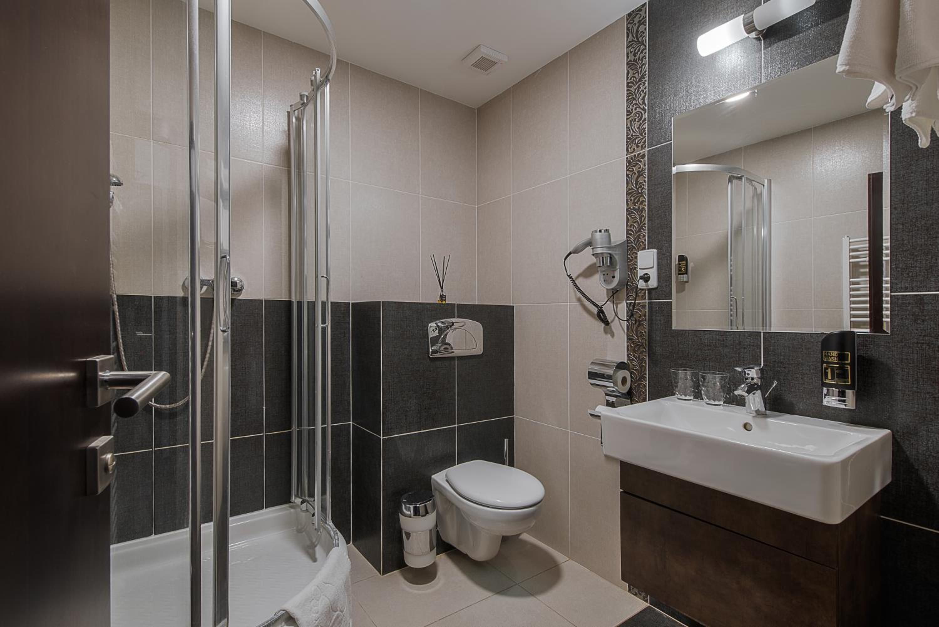 Ein modernes Badezimmer mit einer Duschkabine, einer Toilette und einem Waschbecken mit Spiegel.