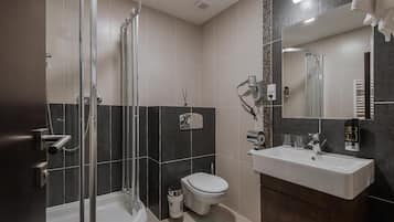 A modern bathroom with a glass-enclosed shower, a toilet, and a sink with a mirror.