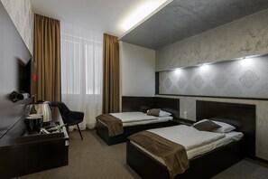 A hotel room with two beds, a desk with a coffee maker, a chair, and a TV. - Hotel Polo (Prešov)