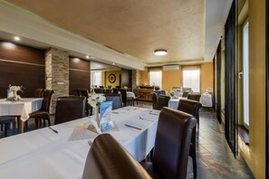 A hotel dining area with multiple tables, chairs, and a clock on the wall. - Hotel Polo (Prešov)