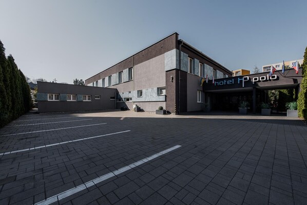 A modern hotel building with a parking lot in front. - Hotel Polo (Prešov)