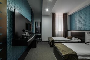 A hotel room with a desk, two beds, a mirror, and a window with curtains. - Hotel Polo (Prešov)