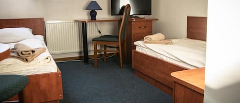 Habitación de hotel con dos camas individuales, un escritorio con silla, un televisor y un radiador.