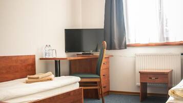 Ein Hotelzimmer mit Bett, Schreibtisch mit Computer, Stuhl, einem kleinen Tisch und einem Heizkörper.