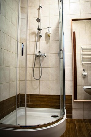 A glass-enclosed shower stall with a handheld showerhead and a wall-mounted faucet. - Hotel Ach To Tu (gmina Święciechowa)