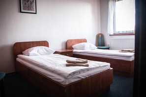 A hotel room with two wooden beds, white bedding, a chair, a small table, and a window with curtains. - Hotel Ach To Tu (gmina Święciechowa)