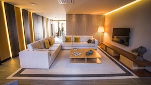 A modern living room with a sectional sofa, a coffee table, and a TV. - Hotel Brazv O (Vila do Conde)