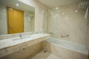 A bathroom with a marble sink, a glass-enclosed shower, and a wooden door. - Hotel Brazv O (Vila do Conde)