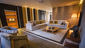 A modern living room with a sectional sofa, a coffee table, and a seating area with chairs. - Hotel Brazv O (Vila do Conde)
