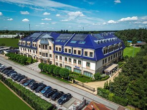 Ein großes Hotel mit mehreren Etagen, einem Parkplatz und einem gepflegten Rasen.