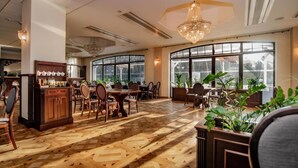 Un comedor amplio con piso de madera, ventanas grandes y una araña.