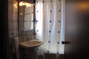 A bathroom with a sink, mirror, and a shower curtain with blue dots. - Hostal Casa Pepe (Tauste)