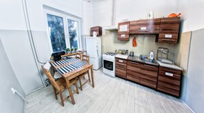 A compact kitchen with a dining table, a stove, and wooden cabinets. - Place4us (Warsaw)