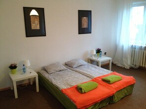 A bedroom with a bed, two nightstands, a window with curtains, and two framed pictures on the wall. - Place4us (Warsaw)