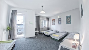 A hotel room with two beds, a desk, a chair, a lamp, and a window with curtains. - Place4us (Warsaw)