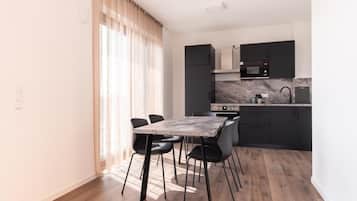 A modern kitchen with a dining area, featuring a marble countertop, black cabinets, and a dining table with chairs.