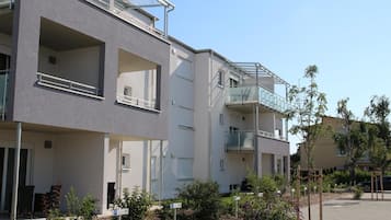 A modern apartment building with balconies, a parking sign, and a clear sky.