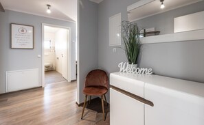 Un interior moderno con piso de madera, un mostrador de recepción blanco, un letrero que dice 'Welcome' y una cita enmarcada en la pared.