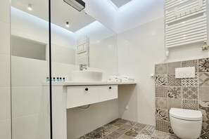 Une salle de bain moderne avec un lavabo blanc, un miroir et des toilettes.