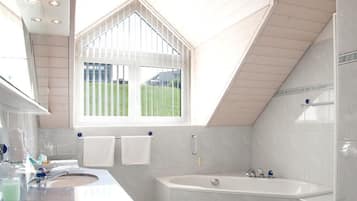 A modern bathroom with a skylight, a bathtub, and a vanity with a sink.