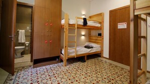 A small, compact room with a bunk bed, a wooden wardrobe, and a bathroom with a toilet and towel rack. - Corner Hostel (Sliema)