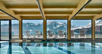 Área da piscina com espreguiçadeiras e vista para as montanhas.