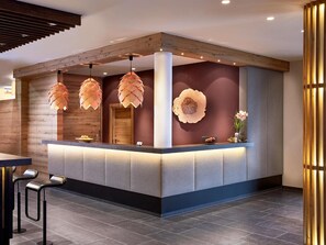 Un comptoir d’accueil au design moderne, agrémenté d’un mur d’accent en bois, d’une grande horloge et de lampes décoratives suspendues.