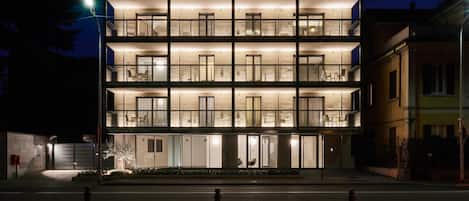 Un hotel de varios pisos con un diseño moderno, que cuenta con balcones en cada planta y una fachada bien iluminada.