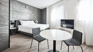 A modern hotel room with a bed, a TV, a round table, and two chairs. - La Perla By Sedar (Como)