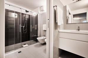 A modern bathroom with a glass-enclosed shower, a white sink, and a mirror above the vanity. - La Perla By Sedar (Como)