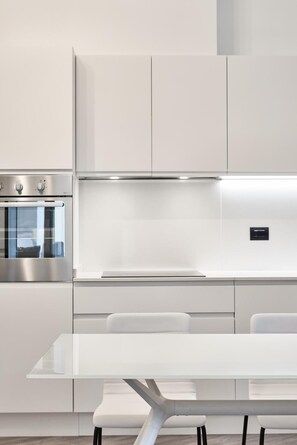 A modern kitchen with a built-in oven, stainless steel cabinets, and a white countertop. - La Perla By Sedar (Como)