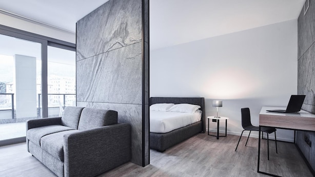 A modern hotel room with a bed, a sofa, a desk, and a chair. - La Perla By Sedar (Como)