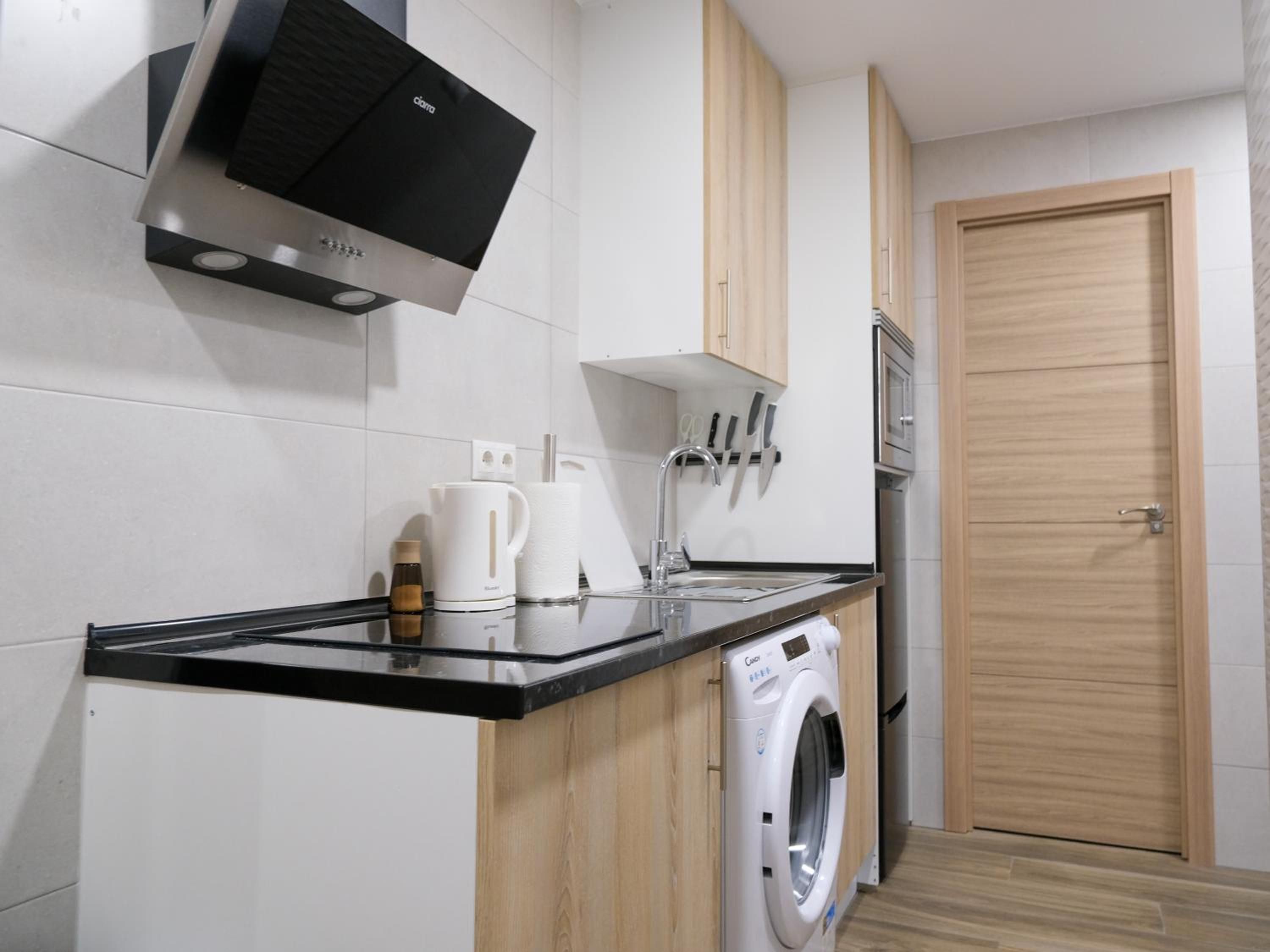 Cocina compacta con lavadora integrada, cafetera y microondas.