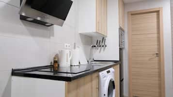Cocina compacta con lavadora integrada, cafetera y microondas.