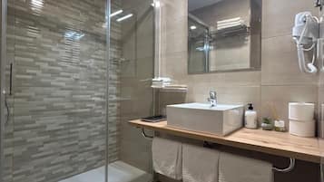 Un baño moderno con cabina de ducha de vidrio, tocador de madera, un espejo grande y teléfono incorporado.