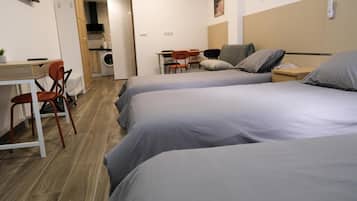 Habitación de hotel con dos camas, un escritorio, una silla y una kitchenette.
