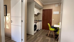 Uma cozinha compacta com máquina de lavar, área de refeições com mesa e cadeiras, e piso de madeira.