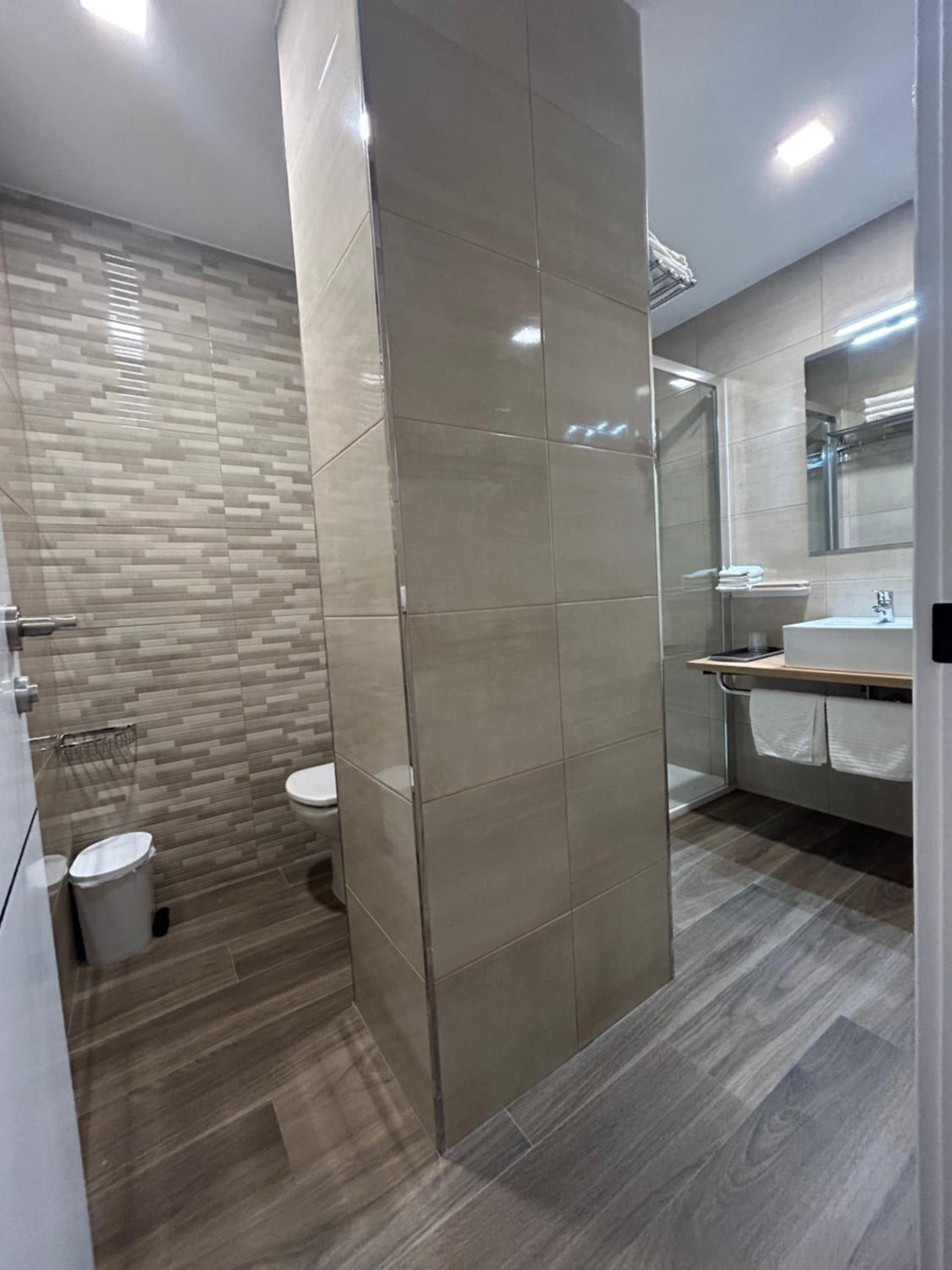 Un baño moderno con cabina de ducha, inodoro y zona de lavabo.