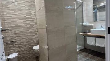Un baño moderno con cabina de ducha, inodoro y zona de lavabo.