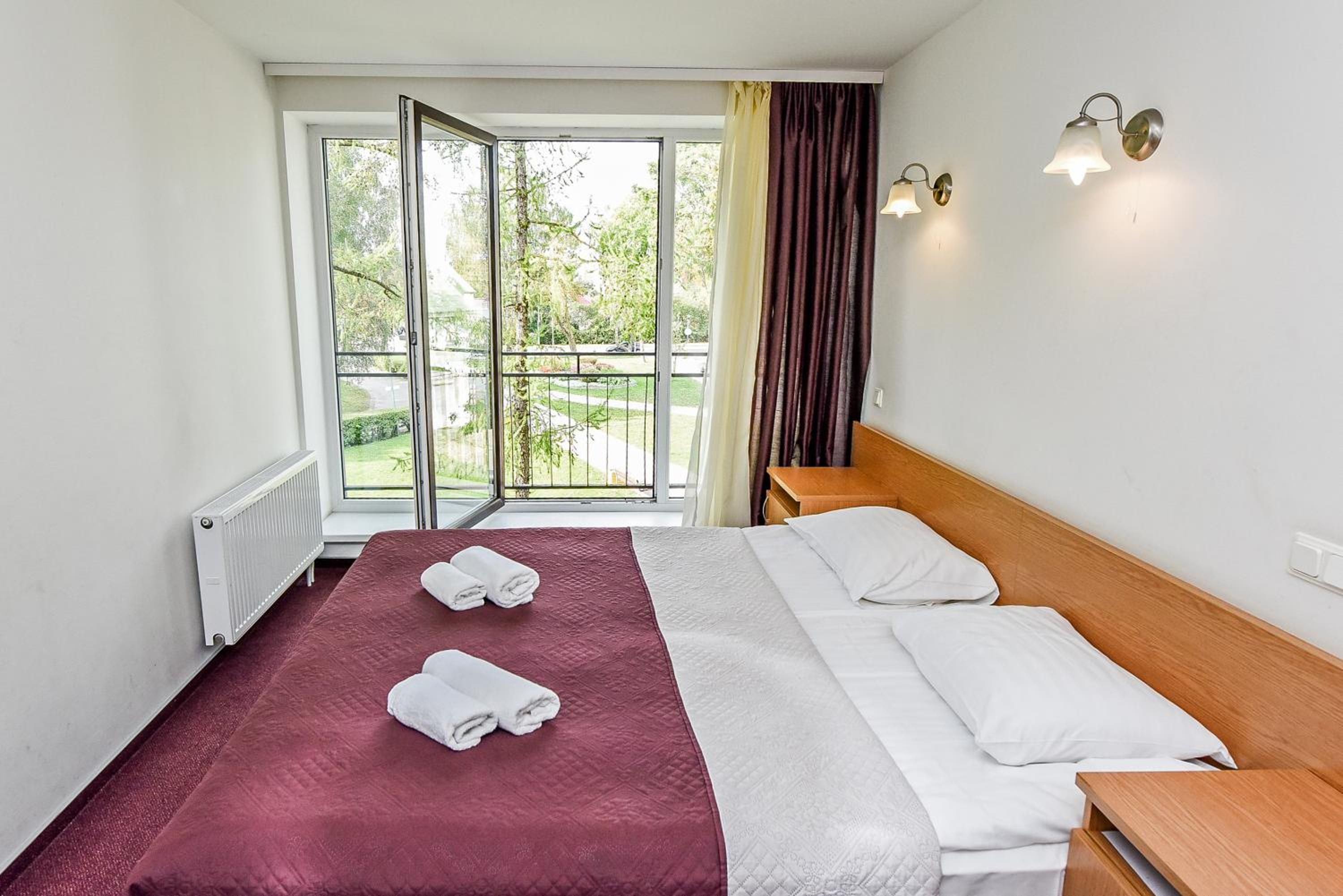 Een hotelkamer met een bed, een raam met uitzicht op de omgeving en een nachtkastje.