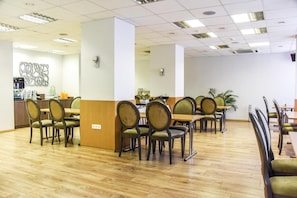 A dining area with wooden flooring, multiple tables, and chairs. - Muza Hotel (Palanga)