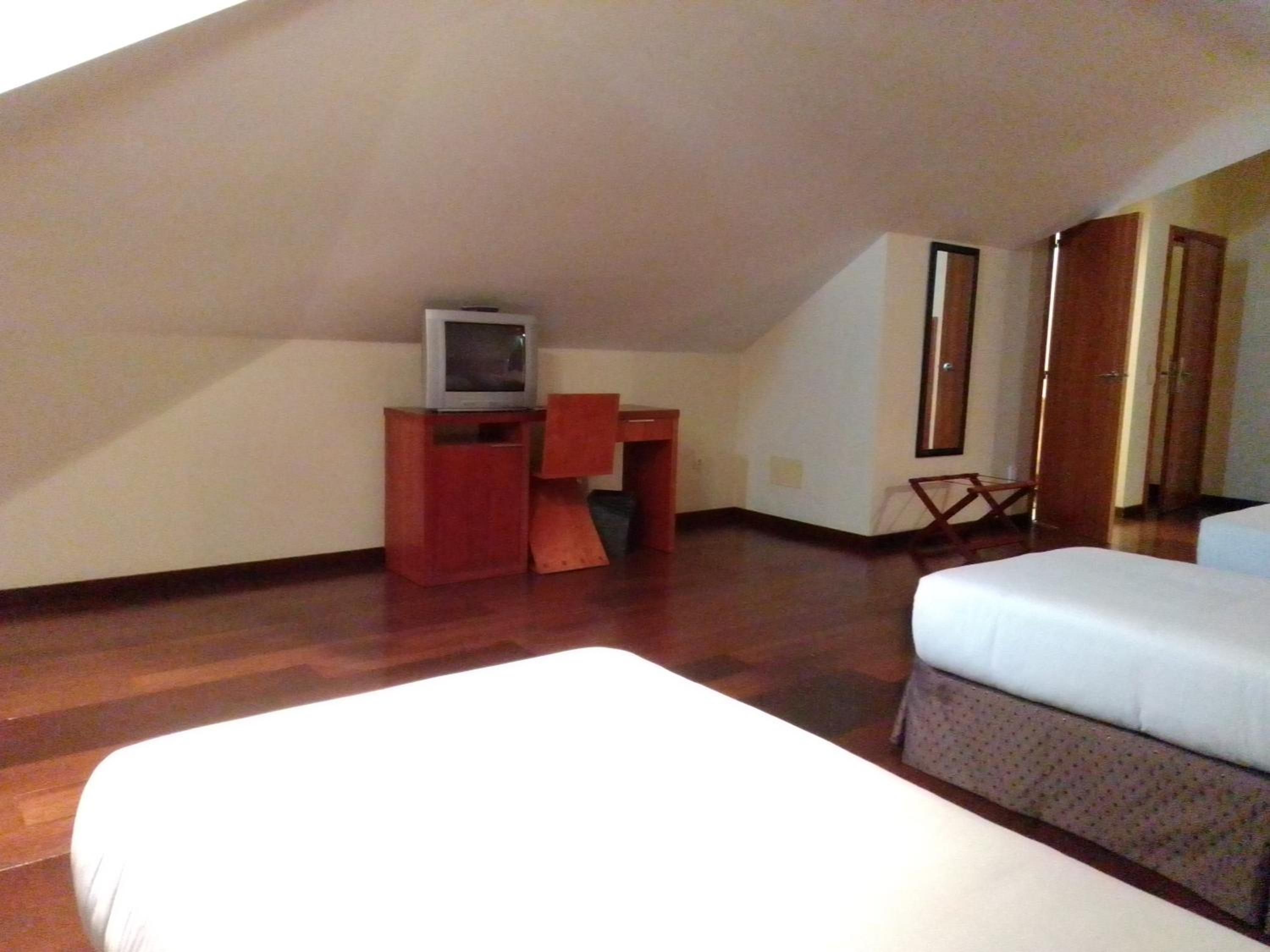 A room with a bed, a desk with a television, and a wardrobe.