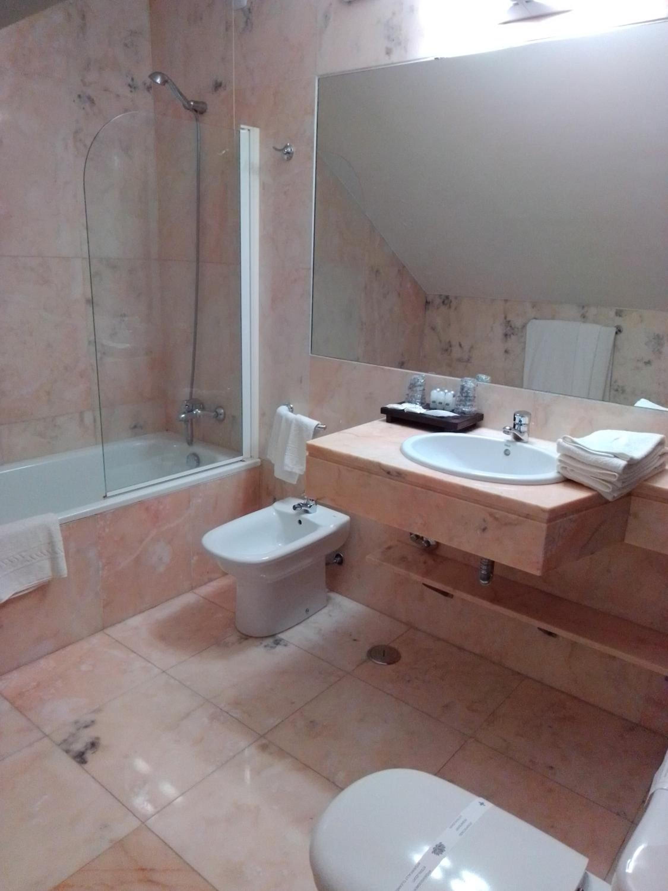 A bathroom with a bathtub, a bidet, a sink, and a toilet.